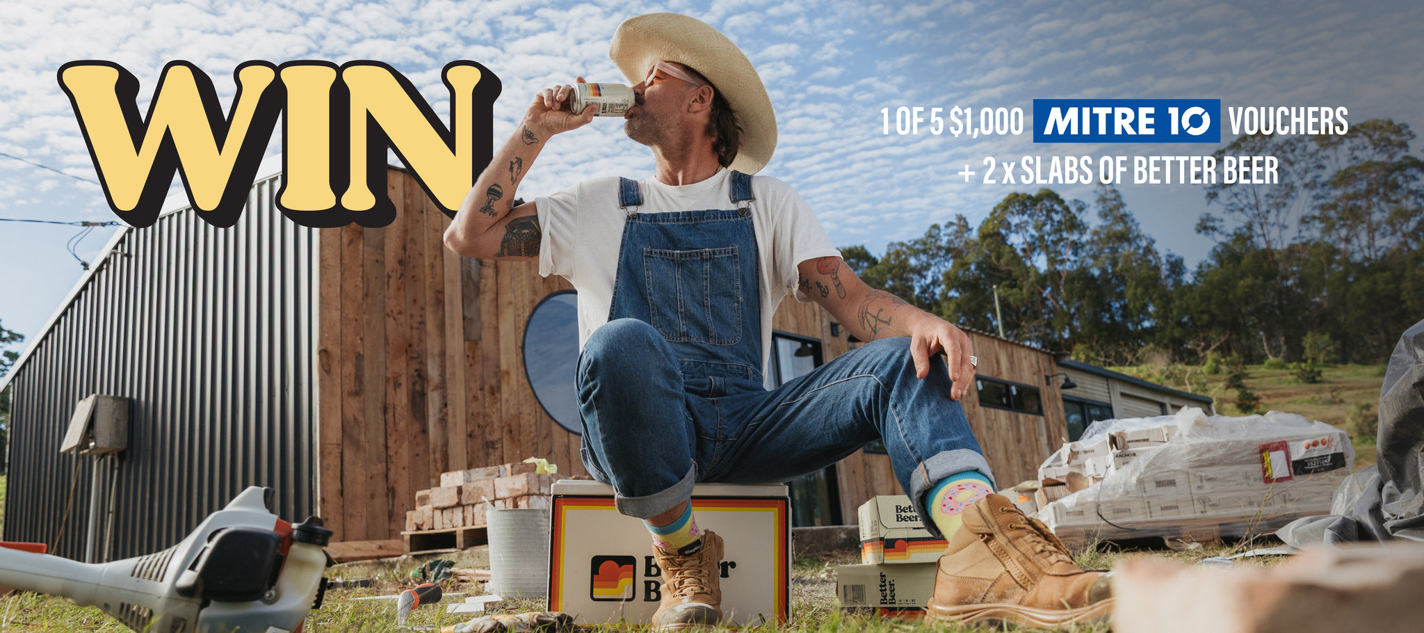 Person in overalls sitting on a box with promotional text for Mitre 10 vouchers and beer in the background.